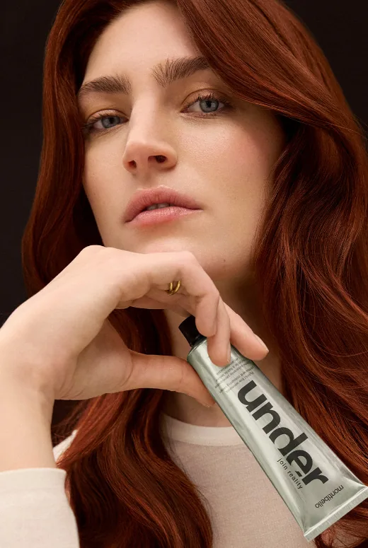 Model with copper red hair holding an Under tube