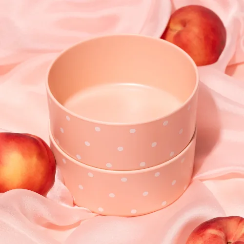 Two stacked Framar Peach Please bamboo colour bowls, peach with white dots, on pink silk